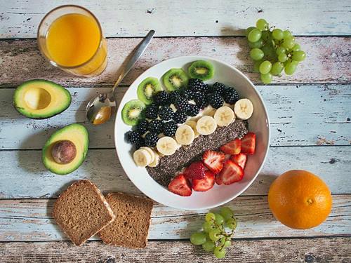 orange juice, whole grain bread, kiwi, mulberries, strawberries and avocado a healthy breakfast