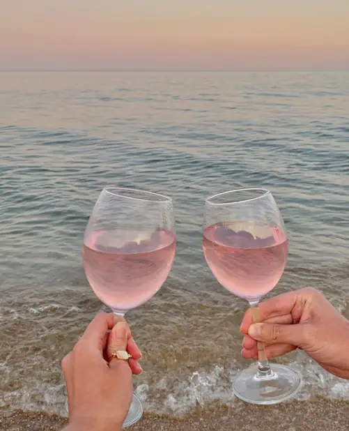 two glasses of wine, sand and the sea at dusk