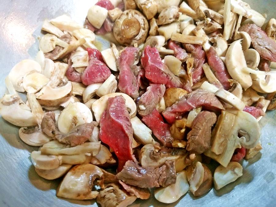 mushrooms and beef simmering in wok