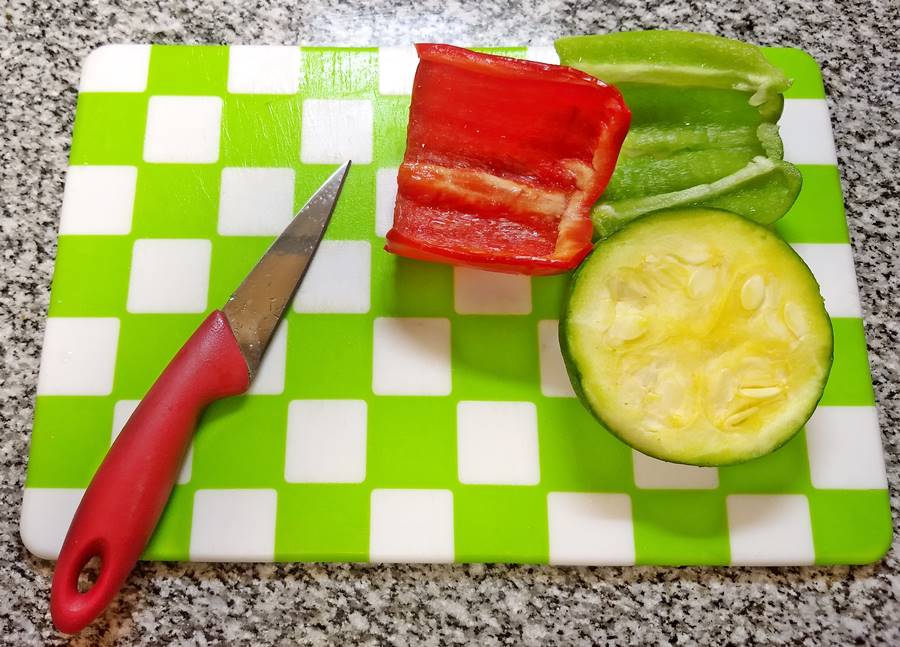 red pepper, green pepper and half a green summer squash on choping board