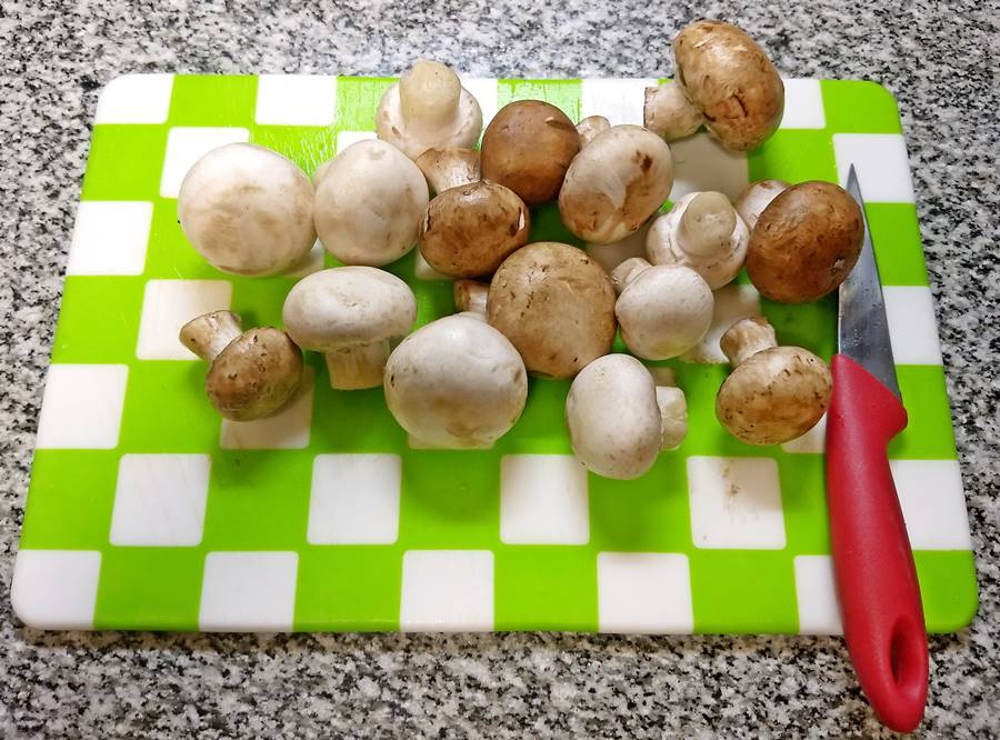 Whole Portobello and button mushroms on chopping board