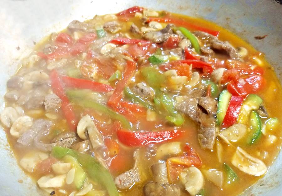 food simmering inside wok