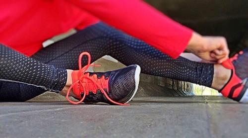 fitness: woman in red gym tights tying her sports shoe laces
