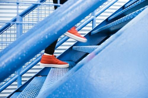 woman's feet in sports shoes climbing up the steps of a metal staircase