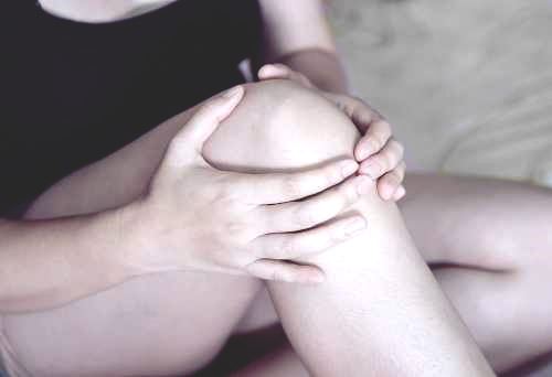black and white woman holds her knee with her hands
