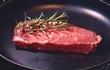 raw steak in pan