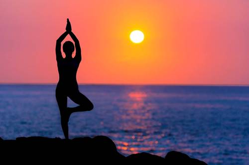 allegory of perfect balance: woman doing yoga pose at sunset