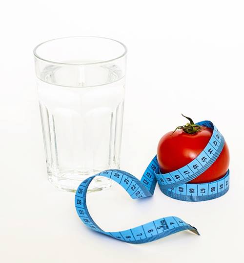 Glass of water, tape measure and tomato:get slim