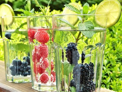 glasses of water with slice of lime, mint and whole berries