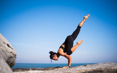 Woman in striking yoga pose handstand by the sea