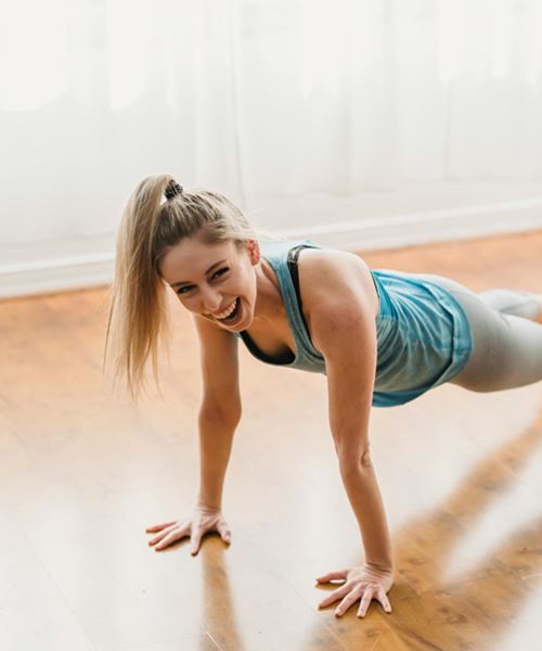 smiling young woman doing plank posture during training